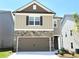 Two-story home featuring stone accents, beige siding, a two-car garage, and a well-maintained lawn at 258 Station Overlook Dr, Auburn, GA 30011