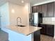 Kitchen island features stainless steel sink, pendant lights and granite countertops at 258 Station Overlook Dr, Auburn, GA 30011