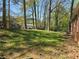 A backyard with tall trees and a grassy area features a brick house with an AC unit installed outside at 251 Banberry Se Dr, Atlanta, GA 30315