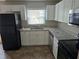 Modern kitchen featuring white cabinets, stainless appliances, granite counters, and a black refrigerator at 251 Banberry Se Dr, Atlanta, GA 30315