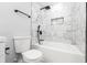 Clean, white bathroom with tub, shower, and tiled walls with a shelf for storage at 661 Inglewood Se Dr, Smyrna, GA 30080