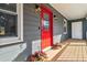 Cozy front porch featuring a vibrant red door with decorative accents, stylish sconces, and potted flowers at 1354 Litchfield Ct, Snellville, GA 30078