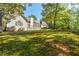 Spacious backyard with lush lawn and mature trees surrounding a white home with a deck at 5440 Shady Grove Rd, Cumming, GA 30041