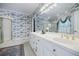 Bright bathroom featuring a double vanity, patterned wallpaper, and a glass-door shower at 5440 Shady Grove Rd, Cumming, GA 30041