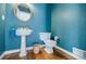 Stylish powder room featuring a pedestal sink, round mirror, and vibrant blue walls at 5440 Shady Grove Rd, Cumming, GA 30041