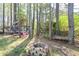 Wooded backyard area with a trampoline, swing, and fire pit, perfect for outdoor activities and relaxation at 6065 Nw Gentlewind Court Nw Ct, Powder Springs, GA 30127