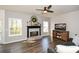 Bright living room with hardwood floors, ceiling fan, fireplace, and a large window overlooking the backyard at 6065 Nw Gentlewind Court Nw Ct, Powder Springs, GA 30127