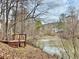 A picturesque view of a pond featuring a wooden deck with a fountain, surrounded by lush trees at 89 Paces Lakes Pt, Dallas, GA 30157
