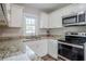 Close up of kitchen featuring granite counters, white cabinets and stainless steel microwave and oven at 3436 Misty Valley Rd, Decatur, GA 30032