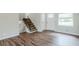 Bright living room featuring vinyl floors, staircase with black railing, front door, and large window at 3436 Misty Valley Rd, Decatur, GA 30032