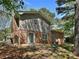 Exterior view showcasing a brick facade, sliding glass door, and patio area surrounded by mature trees for added privacy at 5470 Chanterella Sw Ct, Lilburn, GA 30047