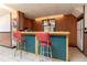 Basement bar area featuring two red stools, wood paneling and a small refrigerator at 10 Flowers Dr, Covington, GA 30014