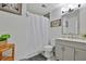 Bright bathroom featuring a shower with a curtain, neutral tiling, and a wooden accent table with a plant at 2344 Johnson Ferry Ne Rd, Atlanta, GA 30341