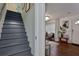 View of a freshly painted gray stairway and an open living room with a charming chandelier and hardwood floors at 2344 Johnson Ferry Ne Rd, Atlanta, GA 30341