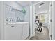 Bright laundry room with side-by-side washer and dryer, open shelving, and doorway to bedroom at 2535 Judson Ave, East Point, GA 30344