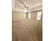 Spacious carpeted primary bedroom featuring a tray ceiling and natural light from multiple windows at 4244 Old House Dr, Conley, GA 30288