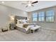Bedroom with a large tufted headboard bed, bench, ceiling fan, and windows with natural light at 516 Cunninghame Ct, Peachtree City, GA 30269