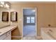 En-suite bathroom with double vanity, soaking tub, and doorway to adjoining room at 1749 Coleville Oak Ln, Lawrenceville, GA 30046
