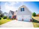 Two-car garage with brick accents, a wide driveway, and green lawn at 207 Meadow Lake Dr, Carrollton, GA 30116