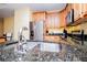 A close up of the stone countertops and stainless steel sink, appliances, and light wood cabinetry at 207 Meadow Lake Dr, Carrollton, GA 30116