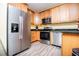 Well-lit kitchen featuring stainless steel appliances, granite counters and light wood cabinetry and plank flooring at 207 Meadow Lake Dr, Carrollton, GA 30116