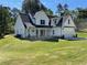 Charming two-story white farmhouse with a well-manicured lawn and welcoming front porch at 1698 Cunningham Sw Rd, Marietta, GA 30008