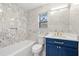 Bathroom features decorative tile surround, blue vanity, and shower-tub combination at 6446 E Windsor Ln, Norcross, GA 30093