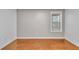 Clean bedroom featuring a window with wood trim, gray walls, and hardwood flooring at 1506 Knights Trl, Stone Mountain, GA 30083