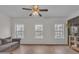 Living room with wood floors, a ceiling fan, windows, and a gray couch at 1506 Knights Trl, Stone Mountain, GA 30083