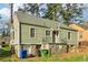 View of the home's side and stone foundation, complete with outdoor trash cans at 1563 Mayflower Sw Ave, Atlanta, GA 30311