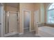 Bright bathroom with neutral tile features a bathtub, glass shower and a large window at 1814 Oak Branch Way, Loganville, GA 30052