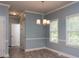 Open-concept dining room with modern chandelier, tiled flooring, white trim, and bright windows overlooking the exterior at 1814 Oak Branch Way, Loganville, GA 30052