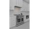 Gourmet kitchen boasts stainless steel appliances, custom white cabinets, patterned floor, and tile backsplash at 2485 Brooks Rd, Dacula, GA 30019