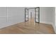 Bright living room features paneled walls, sleek hardwood floors, and framed glass doorways leading to another room at 2485 Brooks Rd, Dacula, GA 30019
