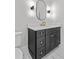 Bathroom vanity featuring modern light fixtures, oval mirror and gold hardware at 2485 Brooks Rd, Dacula, GA 30019