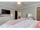 Bright bedroom boasts a white dresser, TV, ceiling fan, and a cozy bed with a plush pink throw at 304 Gilmer Ct, Canton, GA 30115