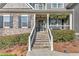 Inviting front porch with stone steps, black door, decorative wreath, and manicured shrubbery at 304 Gilmer Ct, Canton, GA 30115