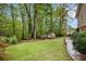 Spacious backyard with a green lawn, mature trees, and a storage shed at 1235 Saint Ives Ct, Suwanee, GA 30024