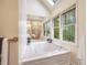Bright bathroom with a luxurious soaking tub, a skylight, and a window looking out to the trees at 1235 Saint Ives Ct, Suwanee, GA 30024