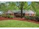 Charming single-story home with brick facade, lush landscaping, and mature trees on a well-maintained lawn at 1235 Saint Ives Ct, Suwanee, GA 30024