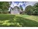 View of the home's rear exterior, set on a sprawling green lawn and complimented by mature trees, perfect for outdoor enjoyment at 51 Muirfield Ct, Hiram, GA 30141