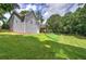 View of the home's rear exterior, set on a sprawling green lawn and complimented by mature trees, perfect for outdoor enjoyment at 51 Muirfield Ct, Hiram, GA 30141