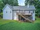 Back exterior view of the home showing a deck, stairs to the yard, and beautiful landscaping at 51 Muirfield Ct, Hiram, GA 30141