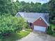 Aerial view of a brick home featuring a well-manicured lawn, mature trees, and an attached two car garage at 51 Muirfield Ct, Hiram, GA 30141