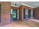 Inviting front porch featuring brick facade, black shutters, and charming curb appeal at 51 Muirfield Ct, Hiram, GA 30141