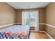 Bedroom with wood trim and a colorful quilt and a large window with curtains at 704 Manor Ridge Dr, Loganville, GA 30052