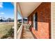 Covered brick front porch with black shutters and a white railing, offering outdoor seating at 704 Manor Ridge Dr, Loganville, GA 30052