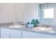 Bright bathroom featuring double sinks, gray countertops, modern fixtures, and stylish blue decorative jars at 12106 Conrad Cir, Hampton, GA 30228