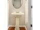 Charming powder room featuring pedestal sink, decorative oval mirror, and wood flooring with decorative trim at 5110 Montcalm Sw Dr, Atlanta, GA 30331