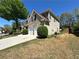 Side exterior of a charming brick home with a well-manicured lawn, two-car garage, and mature trees at 1074 Frog Leap Nw Trl, Kennesaw, GA 30152